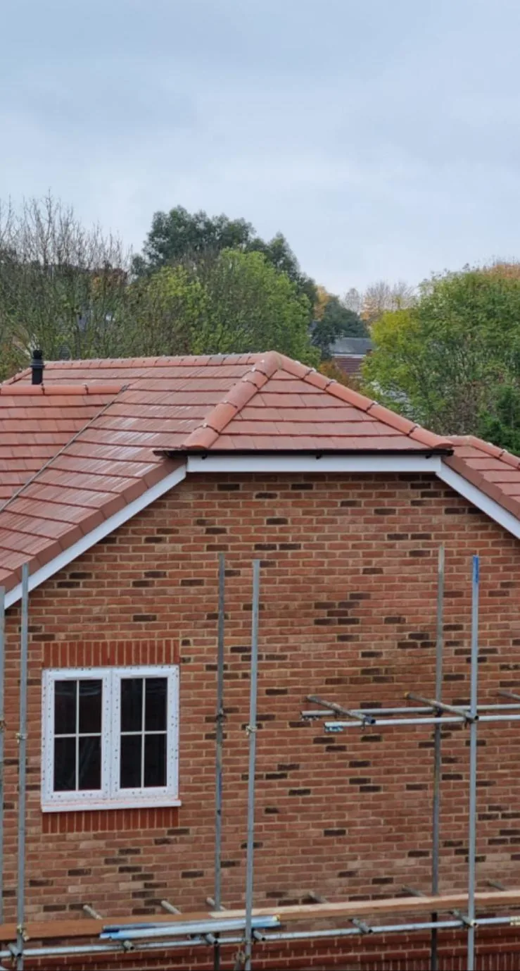 New extension gable with clay roof tiles under scaffold