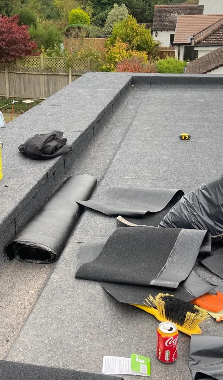 Felt cap sheet rolls being laid on a flat roof