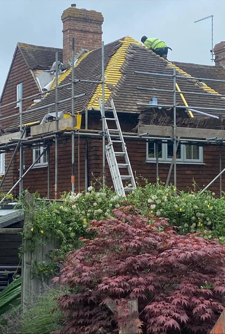 House under scaffold with roof being stripped for a re-roof